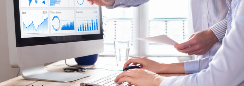 Team of business people discussing digital marketing metrics report and return on investment strategy for advertisement campaign, data analytics dashboard on computer screen in office.