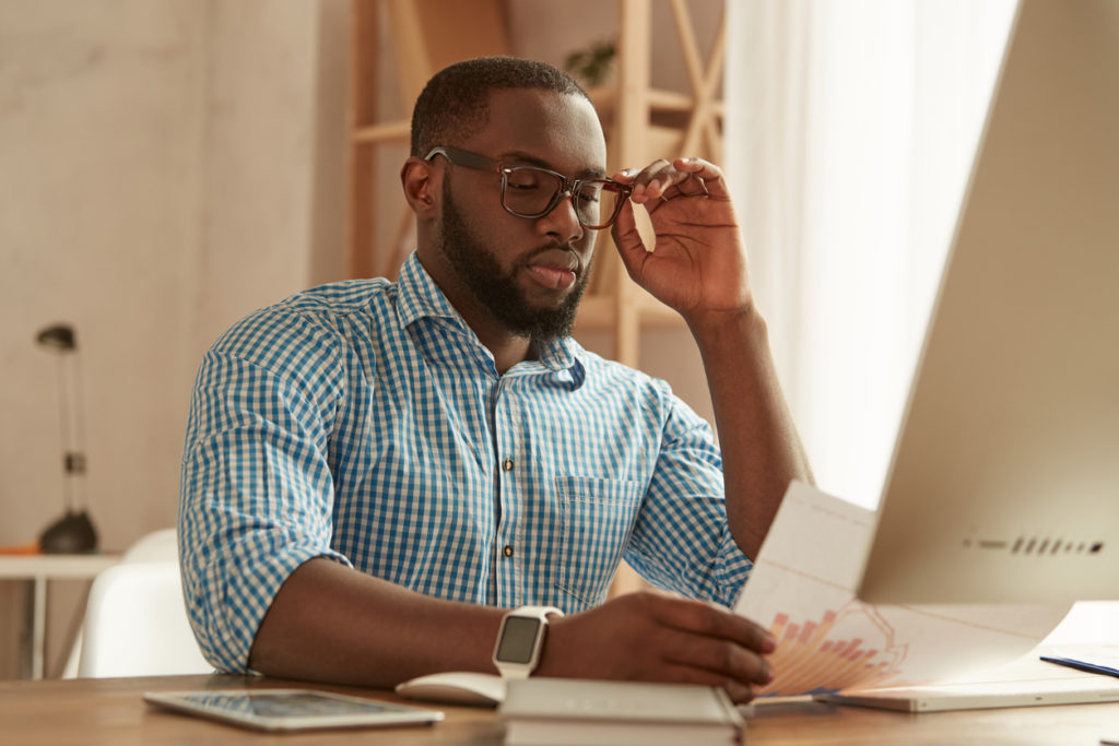 African-American male worker collaborating with colleagues online; remote work efficiency.